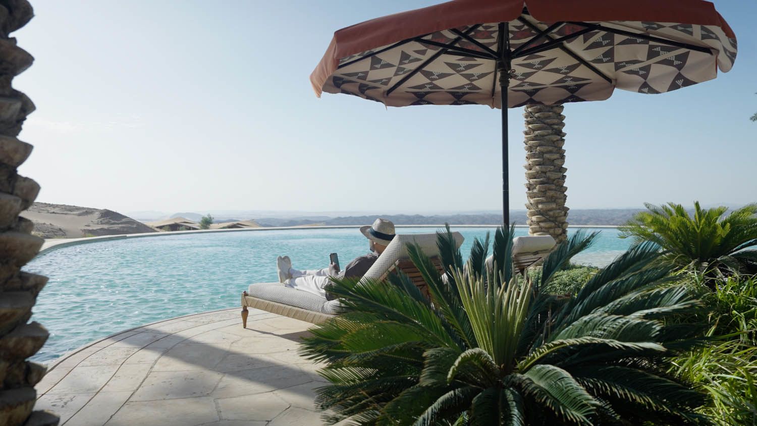 A guest relaxes by a pool, enjoying the serenity and sustainable luxury offered by a destination fully powered by renewable energy.